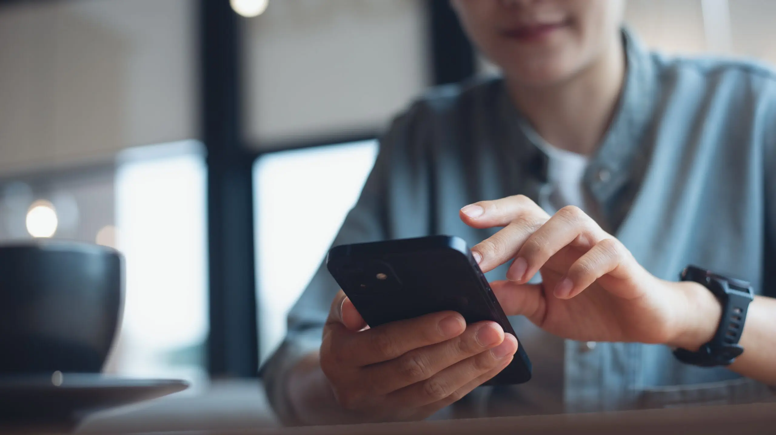 Close,Up,Of,,Woman,Sitting,At,Wooden,Table,Using,Mobile