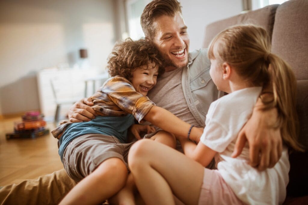 Happy,Father,Hugging,Two,Kids,At,Home